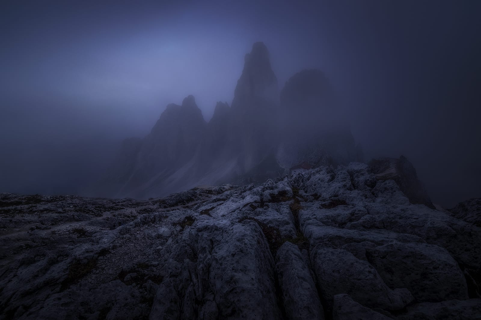 Dark rock towers fading into mist above a rocky plateau